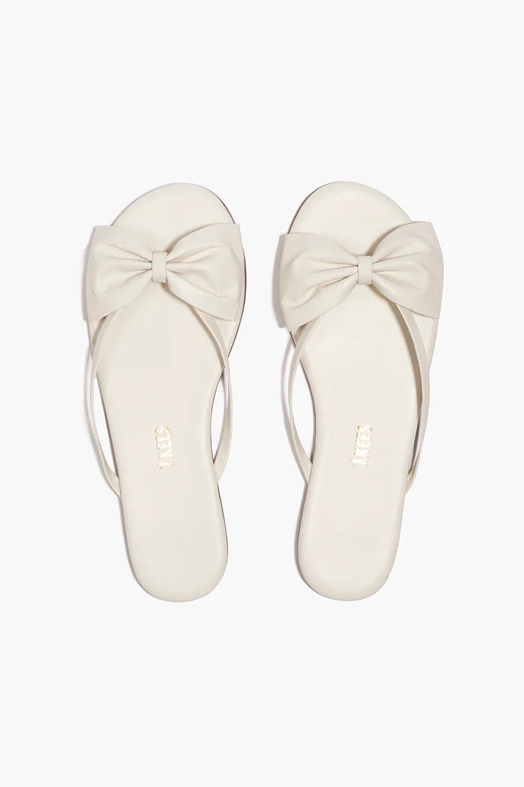 Pair of white sandals with bow details on a white background