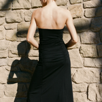 Woman in a black dress standing against a stone wall