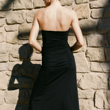 Woman in a black dress standing against a stone wall