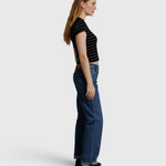 JONES + CO Lisa Tee in black with white stripes, worn by a woman with blue jeans against a neutral fabric backdrop.