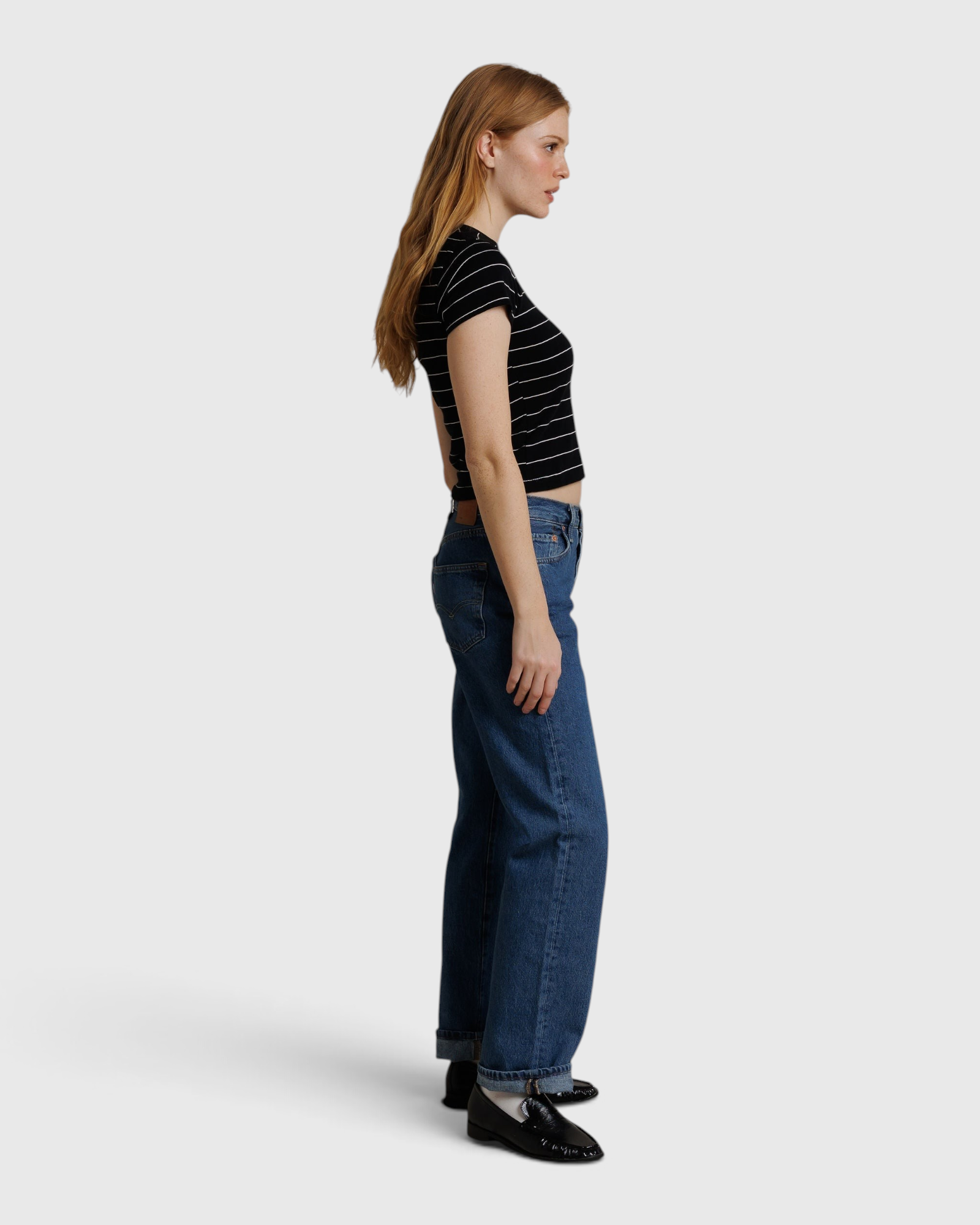 JONES + CO Lisa Tee in black with white stripes, worn by a woman with blue jeans against a neutral fabric backdrop.