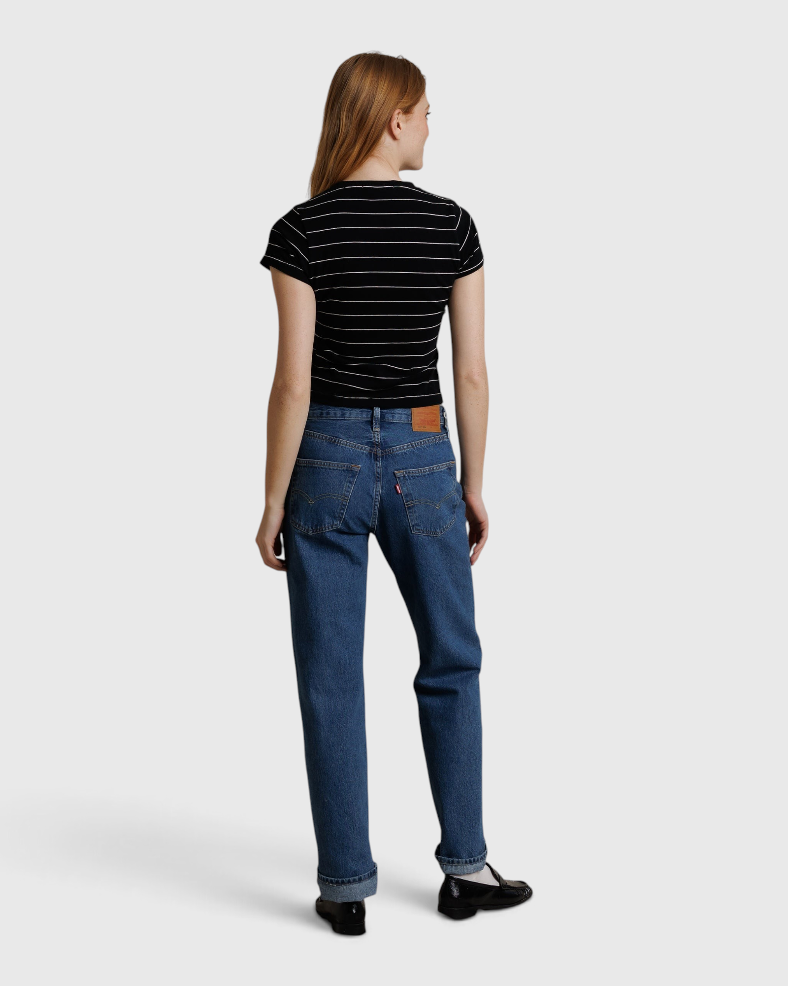 JONES + CO Lisa Tee in black with white stripes, worn by a model from behind with blue jeans and black shoes.