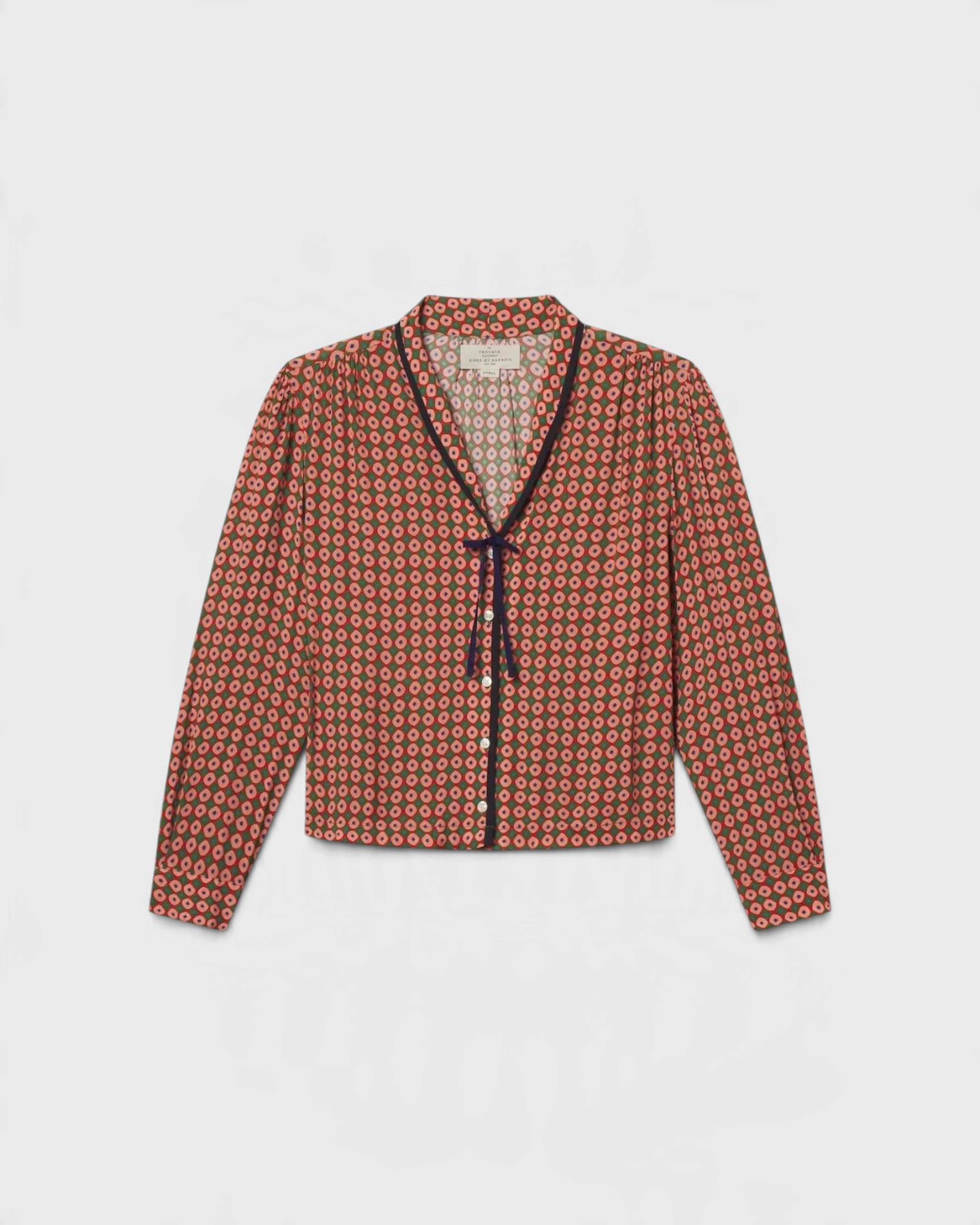JONES + CO Lottie blouse in green, red, and cream geometric print with a V-neck and navy contrast tie detail.