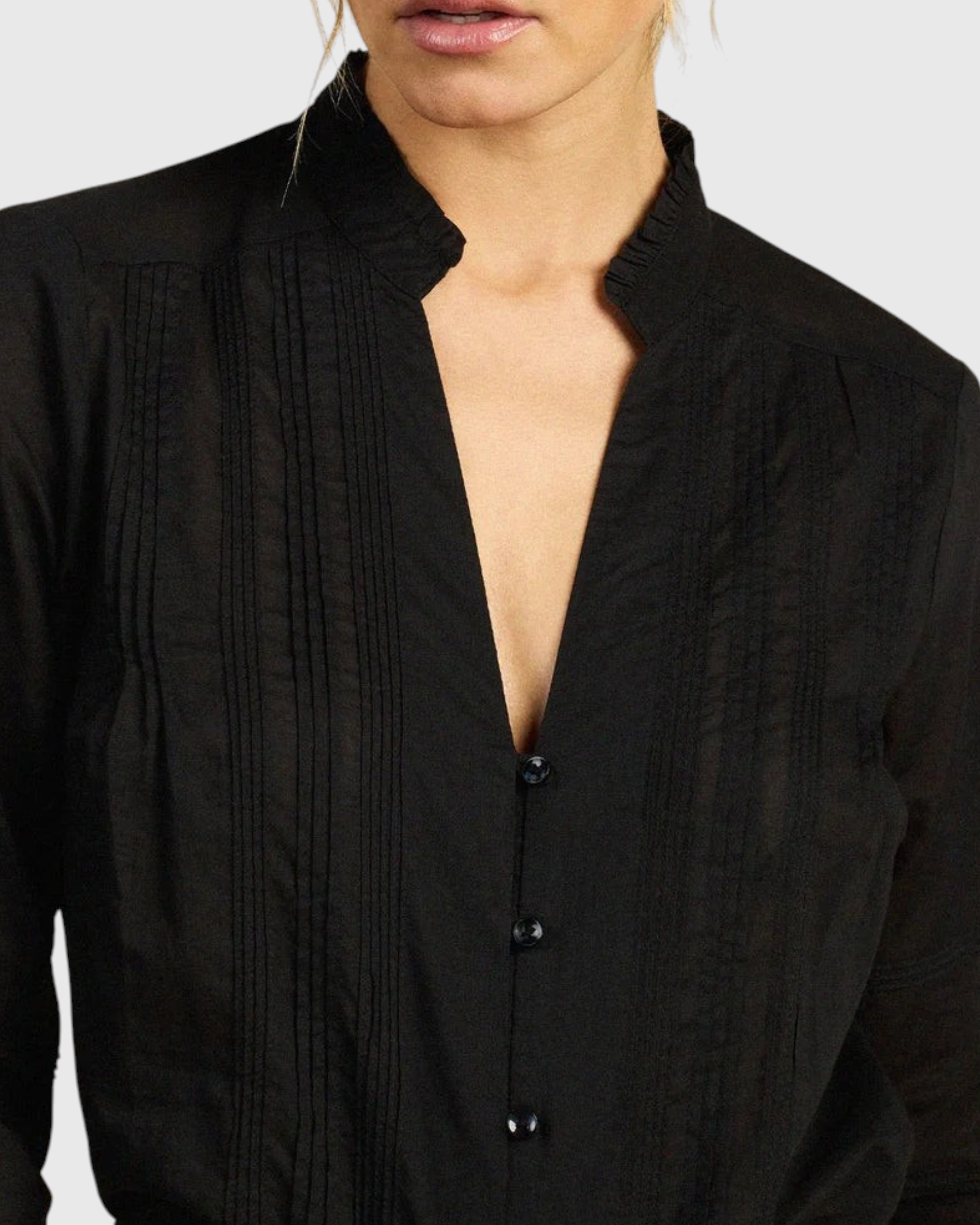 JONES + CO black Maris blouse featuring a ruffled stand collar, vertical pintuck detailing, and a button-down front.