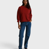 JONES + CO ruby red fleece pullover with bubble sleeves worn by a model with blue jeans against a neutral backdrop