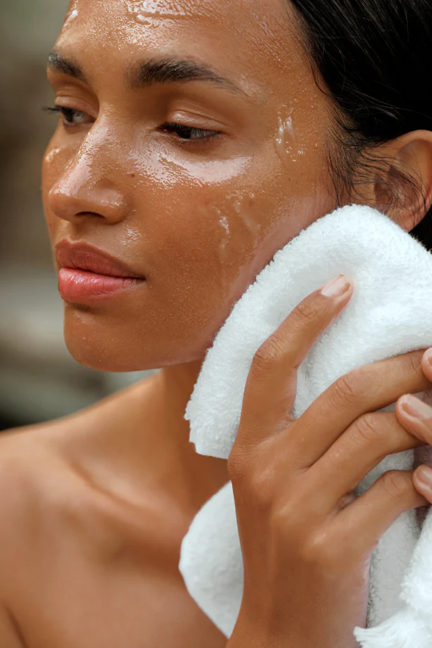 Woman holding a white towel to her face with a blurred background
