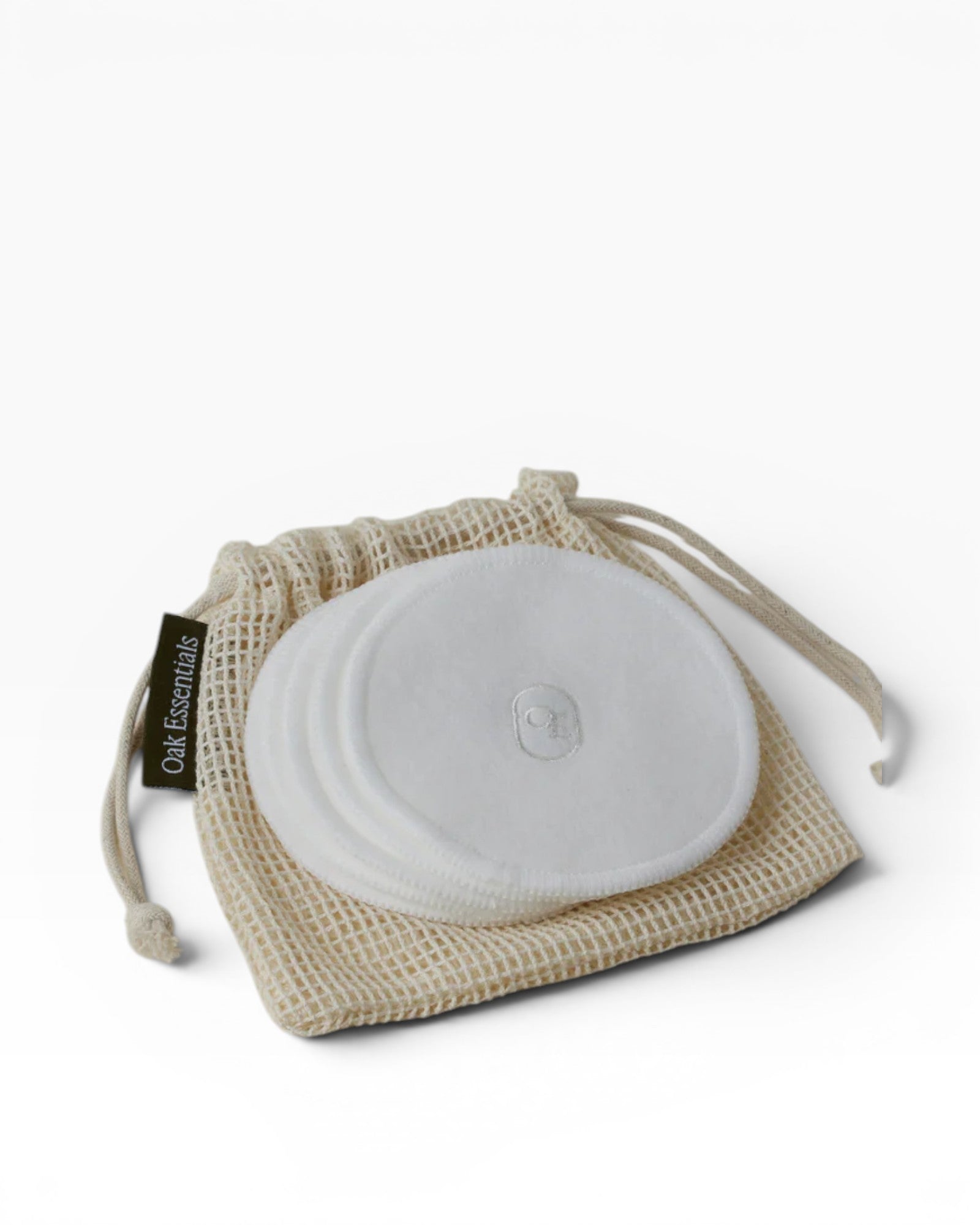 Reusable cotton pads in a mesh bag on a beige background