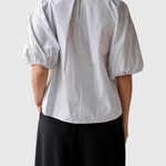 Back view of JONES + CO Lanson white cotton top with short bubble sleeves, grid pattern, and button neck detail