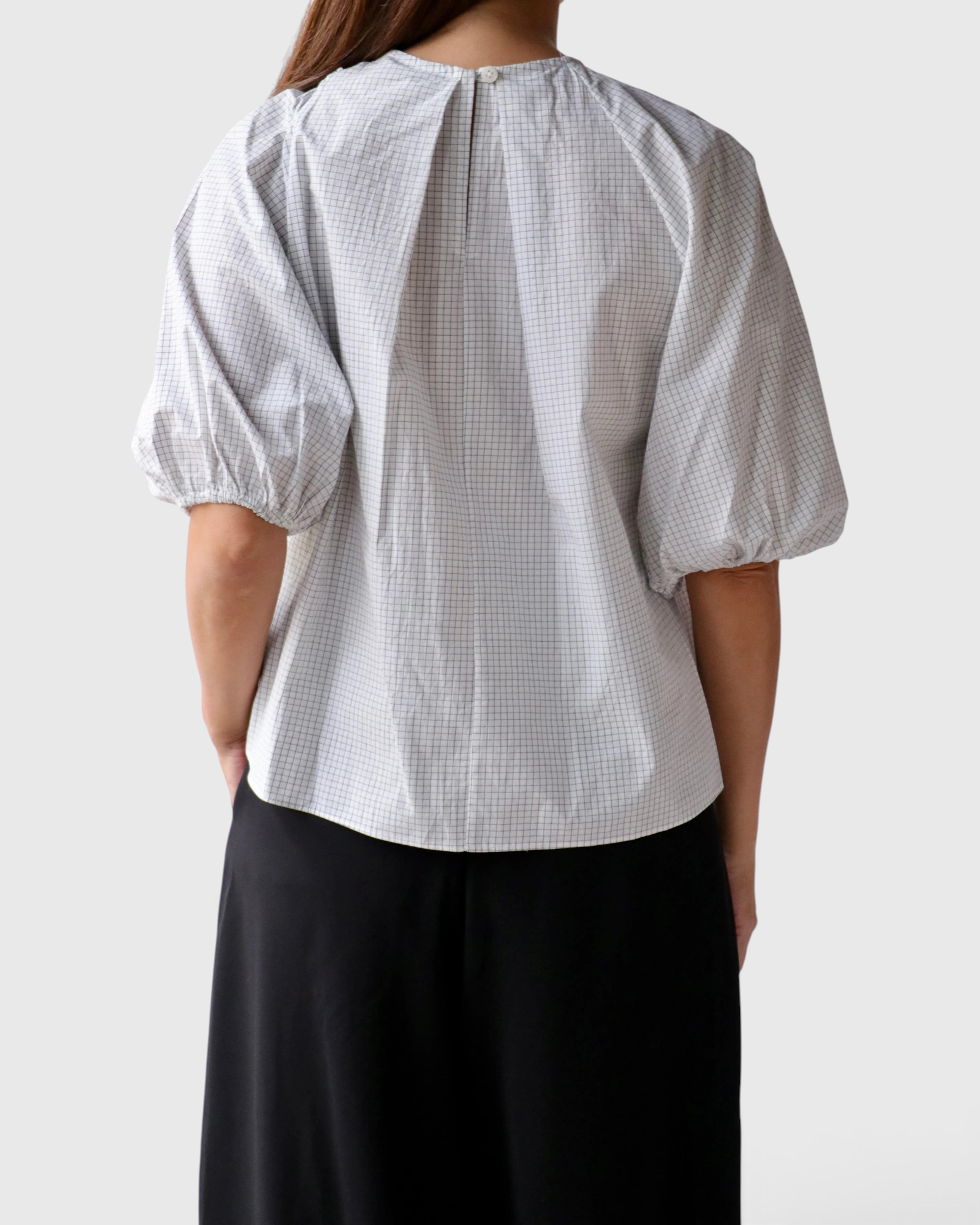 Back view of JONES + CO Lanson white cotton top with short bubble sleeves, grid pattern, and button neck detail