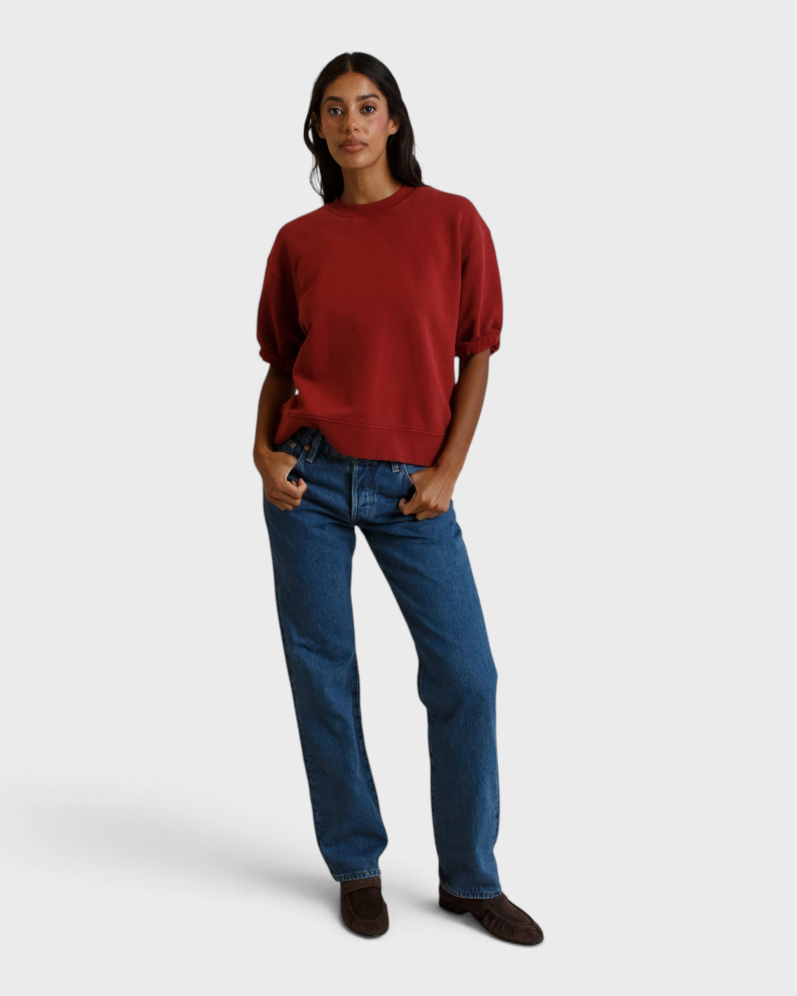 Model wearing a JONES + CO ruby red French terry sweatshirt with three-quarter puff sleeves and blue jeans