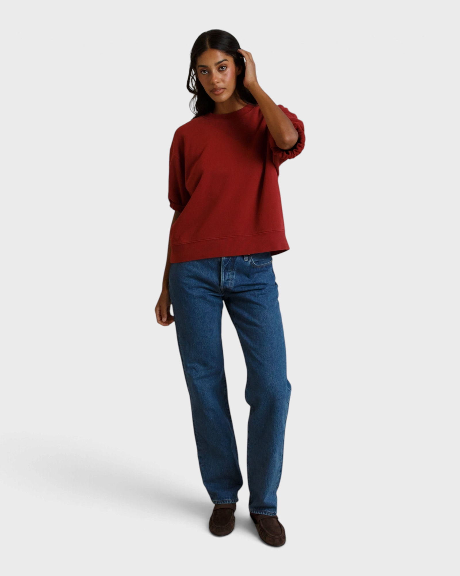 Model wearing a JONES + CO ruby red French terry sweatshirt with three-quarter puff sleeves and blue jeans