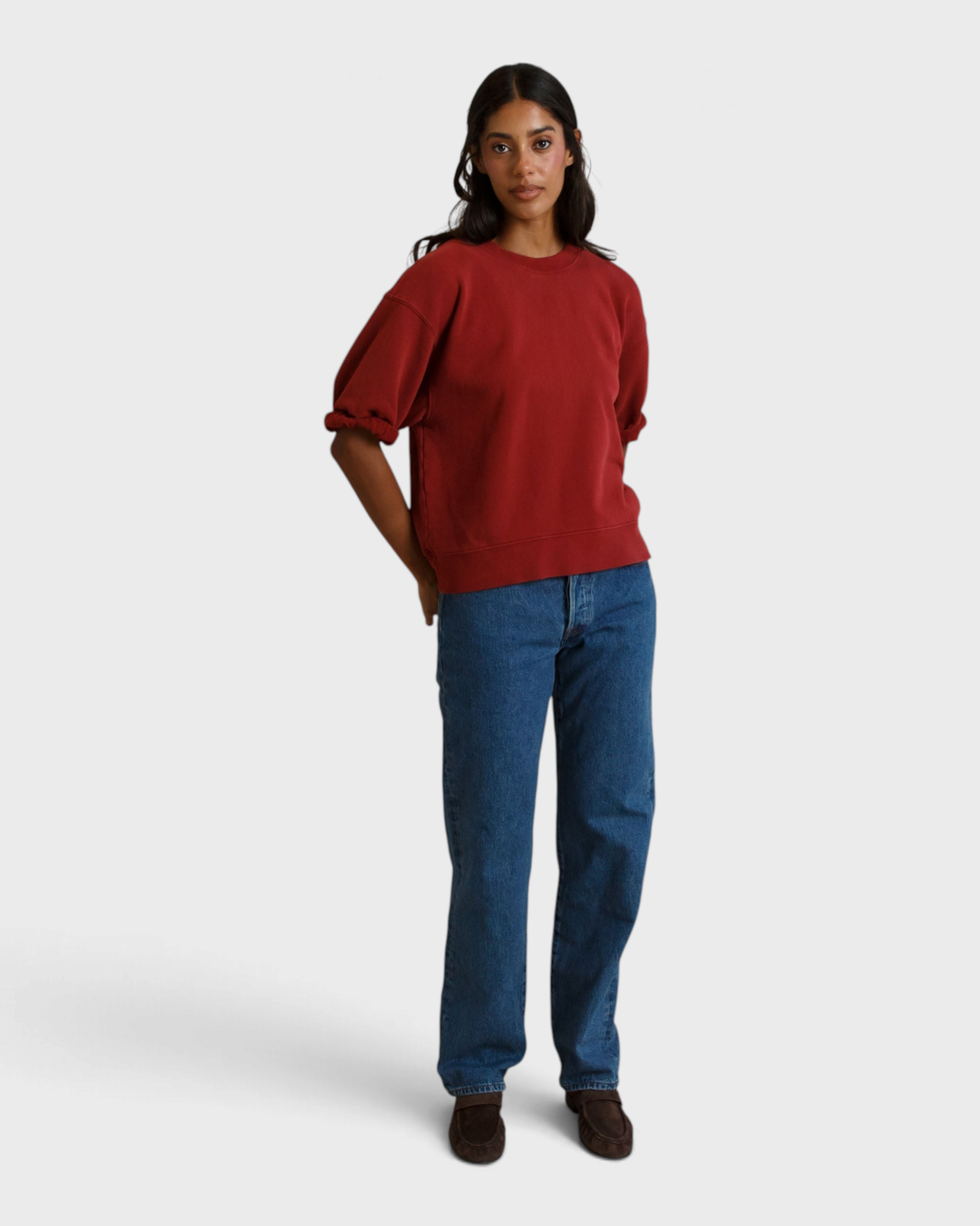 Model wearing a JONES + CO ruby red French terry sweatshirt with three-quarter puff sleeves and blue jeans
