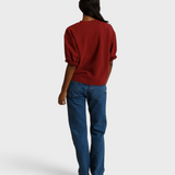 Back view of a woman wearing a JONES + CO ruby red French terry sweatshirt with three-quarter puff sleeves.