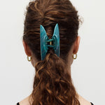 Teal hair clip in a person's hair on a white background