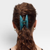 Teal hair clip in a person's hair on a white background