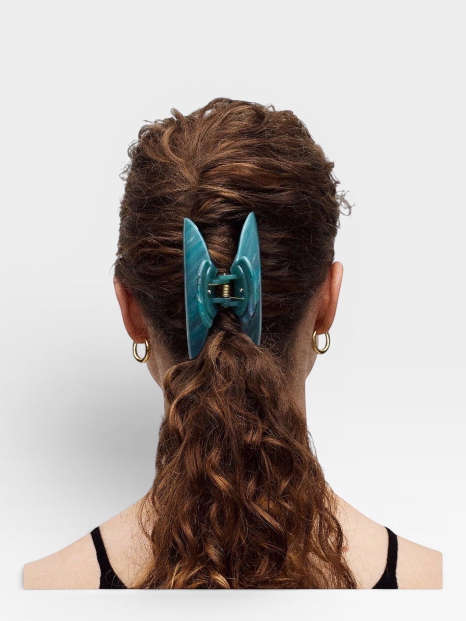Teal hair clip in a person's hair on a white background