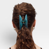 Teal hair clip in a person's hair on a white background