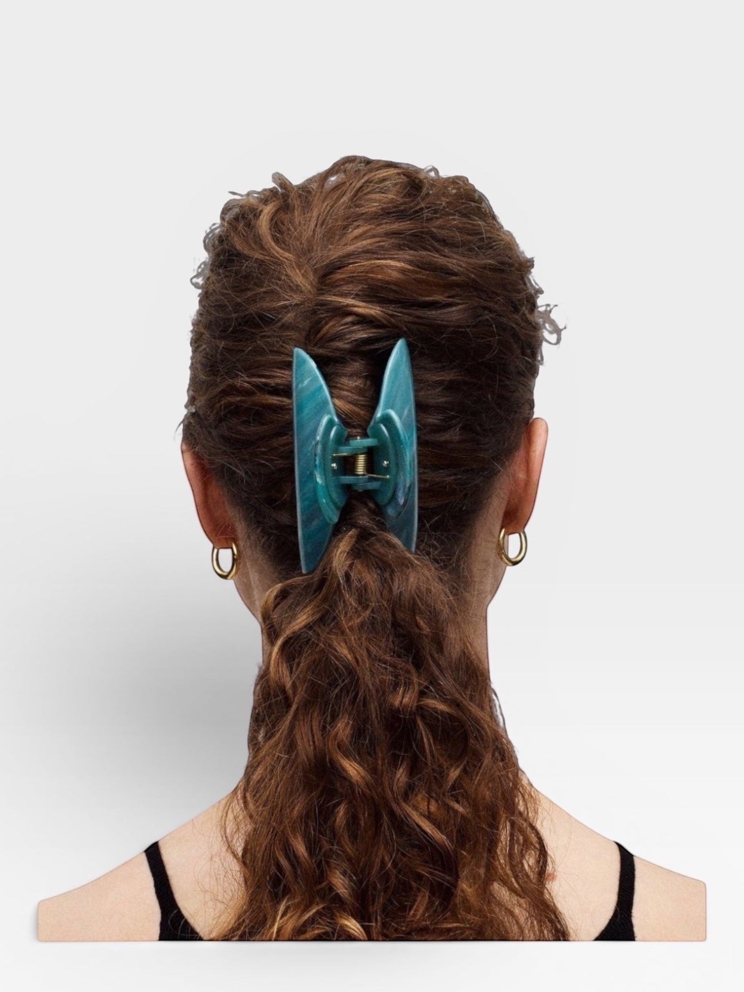 Teal hair clip in a person's hair on a white background