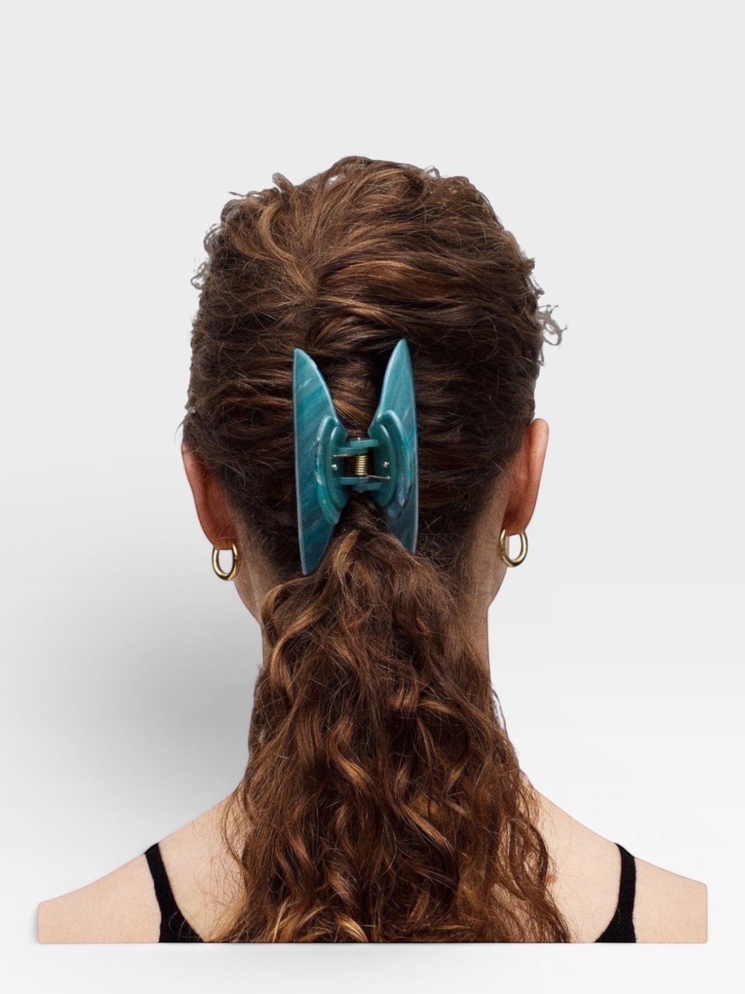 Teal hair clip in a person's hair on a white background