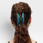 Teal hair clip in a person's hair on a white background