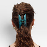 Teal hair clip in a person's hair on a white background