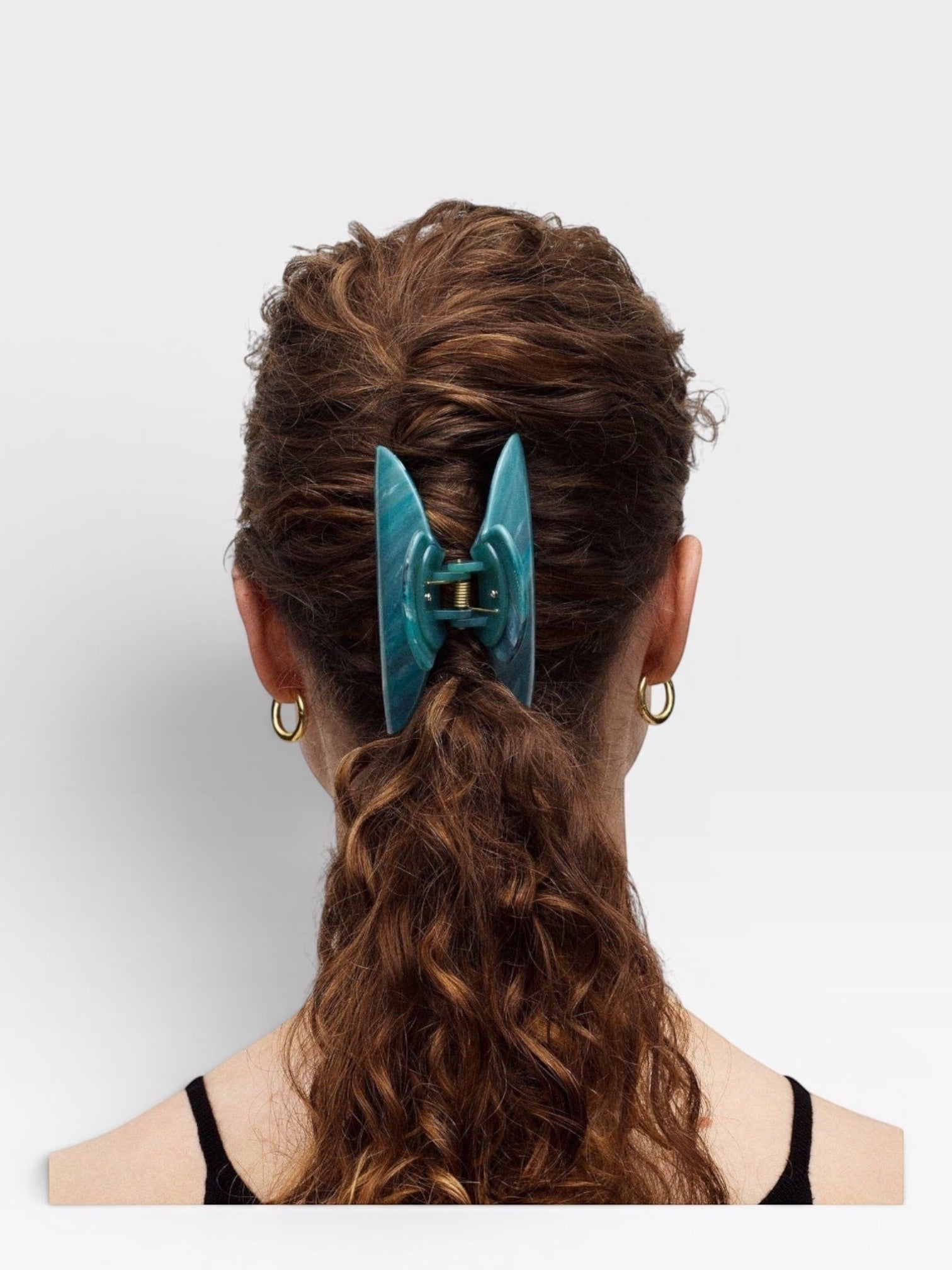 Teal hair clip in a person's hair on a white background