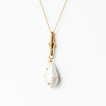Gold necklace with a white pendant on a white background