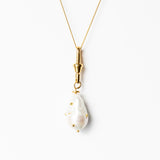 Gold necklace with a white pendant on a white background