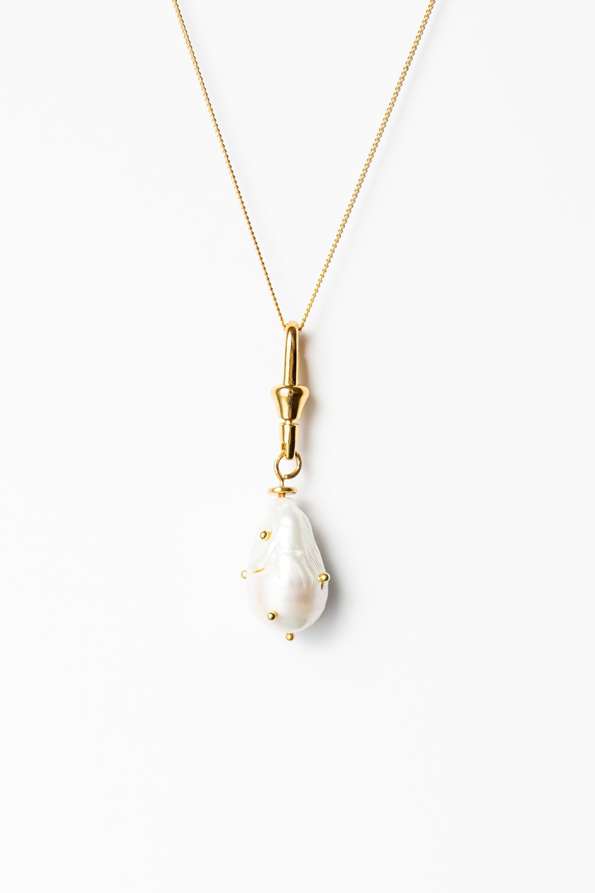 Gold necklace with a white pendant on a white background