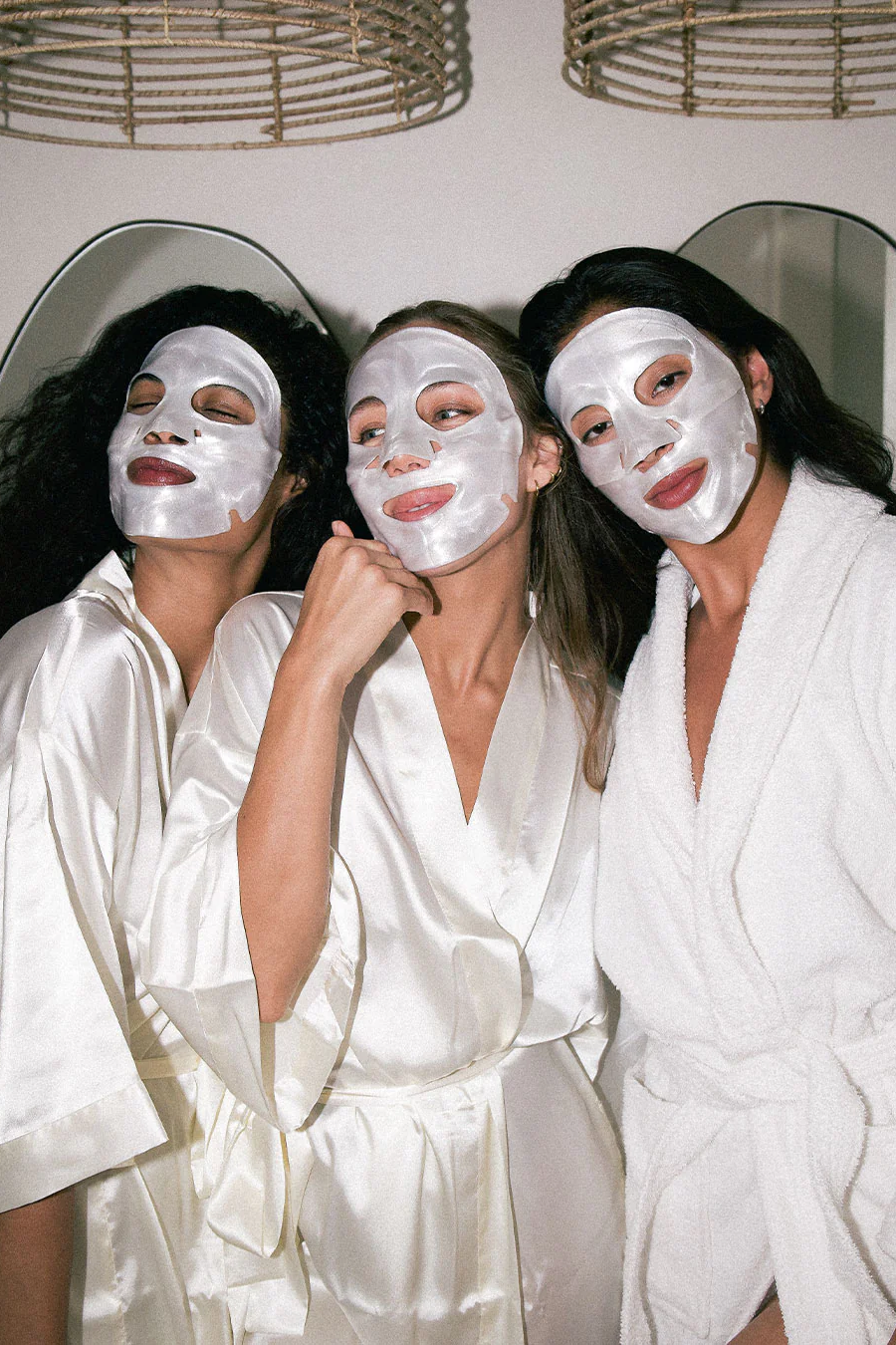 Three women wearing white face masks and robes in a spa setting.