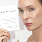 Woman wearing AMETTA SKIN eye masks with a product packaging in the background