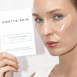 Woman wearing AMETTA SKIN eye masks with a product packaging in the background