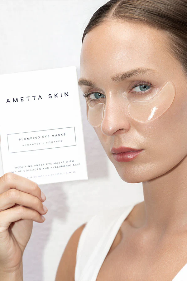 Woman wearing AMETTA SKIN eye masks with a product packaging in the background