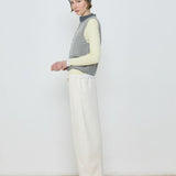 Person wearing a colorful sweater and white pants against a plain background