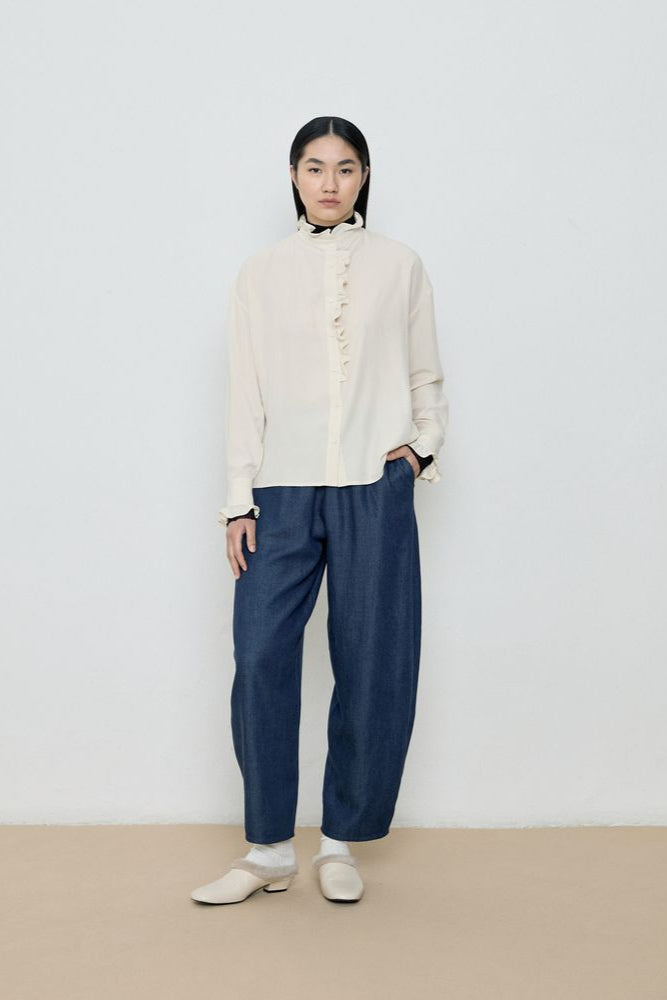 Person wearing a cream sweater and blue pants against a white background