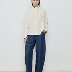 Person wearing a cream sweater and blue pants against a white background