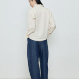 Person wearing a white blouse and blue pants against a plain background