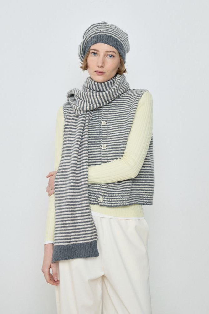 Person wearing a striped scarf, vest, and hat on a white background