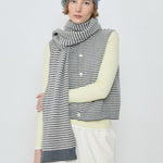 Person wearing a striped scarf, vest, and hat on a white background
