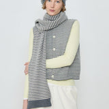 Person wearing a striped scarf, vest, and hat on a white background