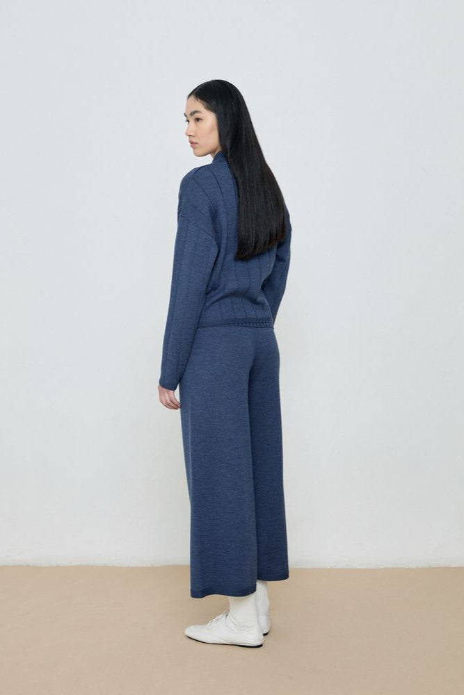 Woman wearing a blue outfit standing against a white background