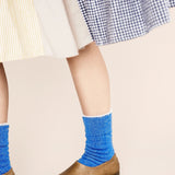 Person wearing blue socks and brown shoes on a beige background
