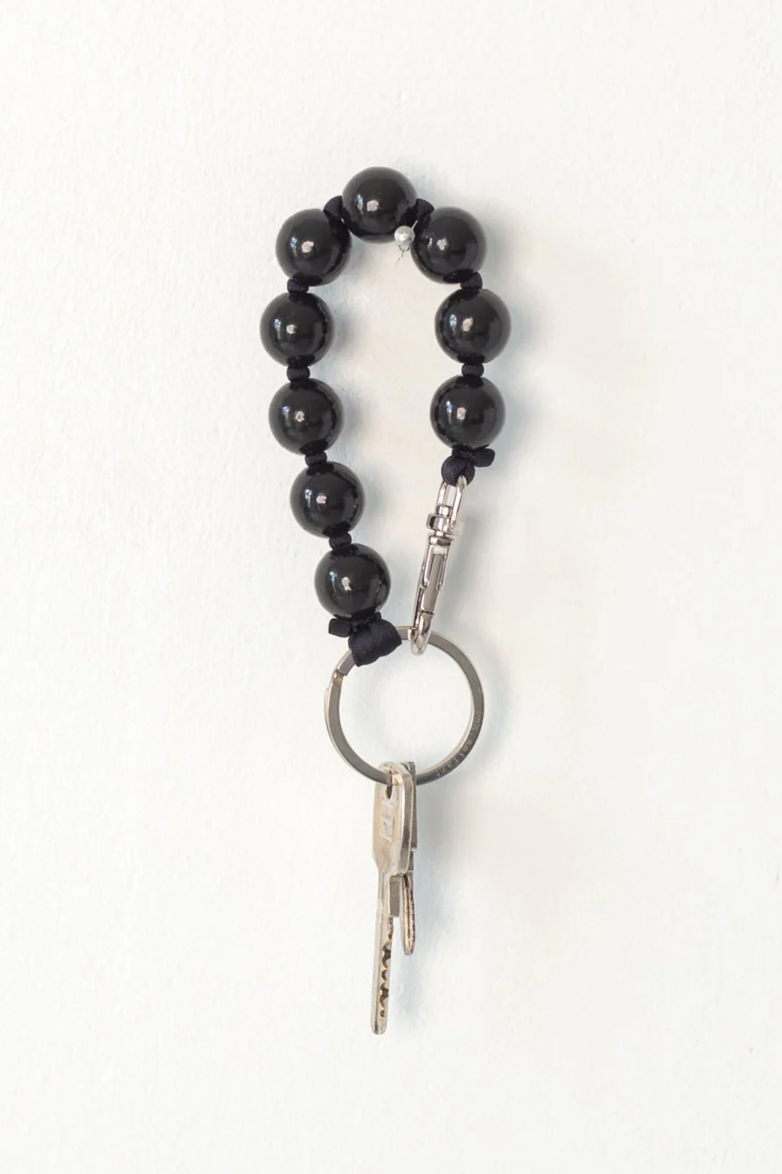 Black beaded ina.seifart keychain with a key on a white background
