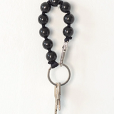 Black beaded ina.seifart keychain with a key on a white background
