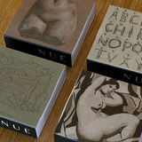 Four boxes with artistic designs and 'NUE' branding on a wooden surface