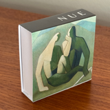 Product packaging with abstract art design and 'NUE' branding on a wooden surface