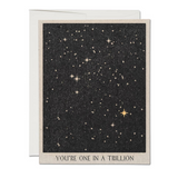 A greeting card with a starry night sky illustration and the text 'YOU'RE ONE IN A TRILLION' on the front.