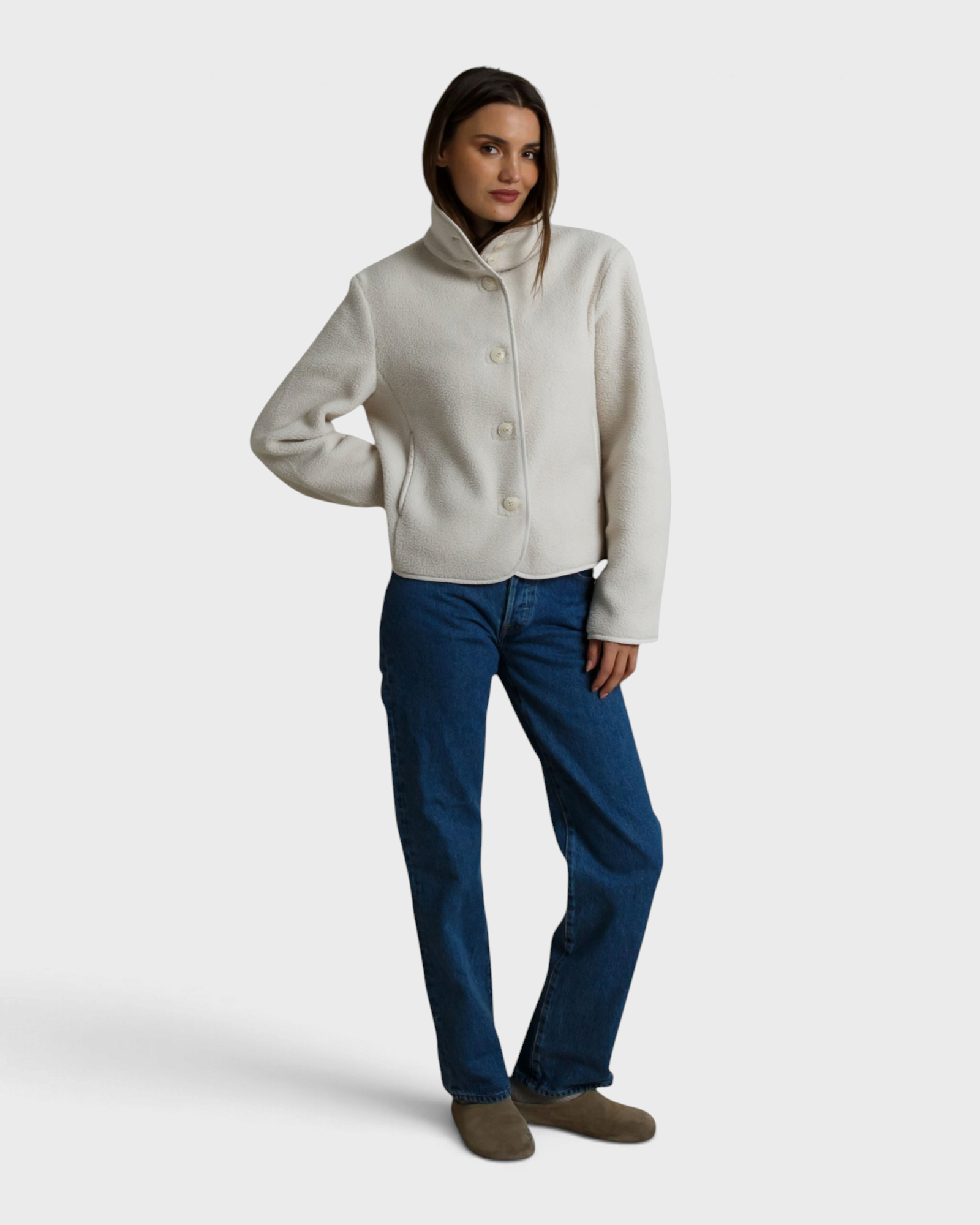 Model wearing a JONES + CO sugar white sherpa button-front jacket with a high collar and blue jeans