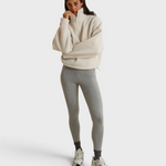 Model wearing a JONES + CO Tristan sherpa half-zip pullover in sugar cream with grey leggings and sneakers