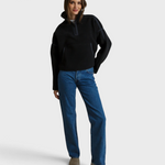 Model wearing a JONES + CO Tristan black sherpa half-zip pullover with blue jeans and neutral slip-on shoes.